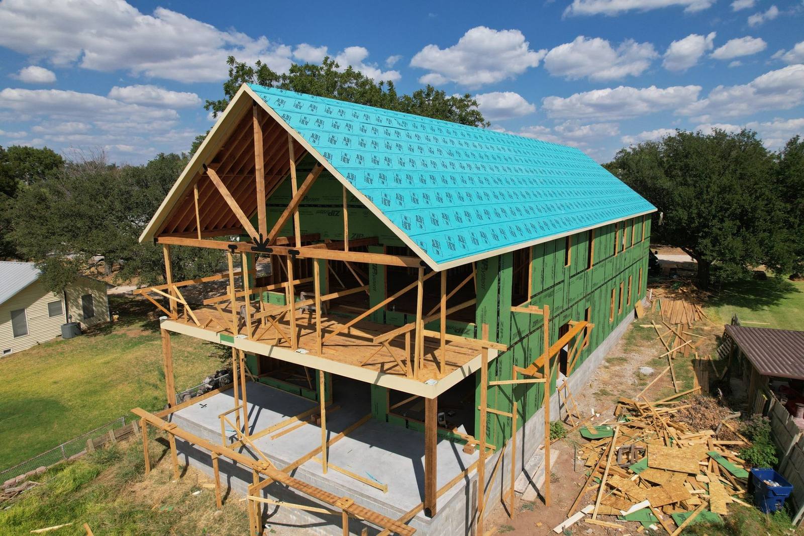 Two-story custom lake house on Possum Kingdom Lake under construction with heavy timber gable trusses and covered porches